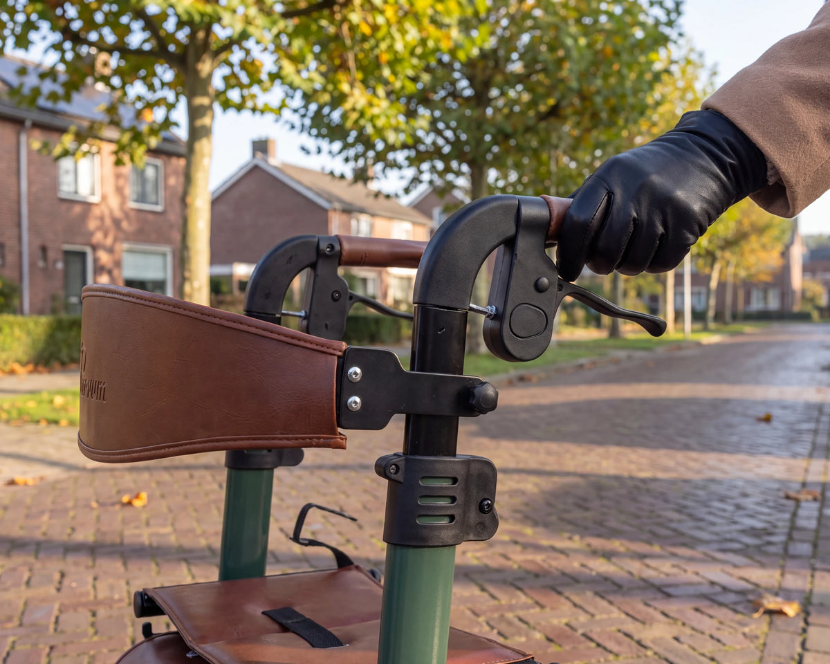 A hand in a black leather glove on the cognac handle of the Parvum Vesta in moss green.