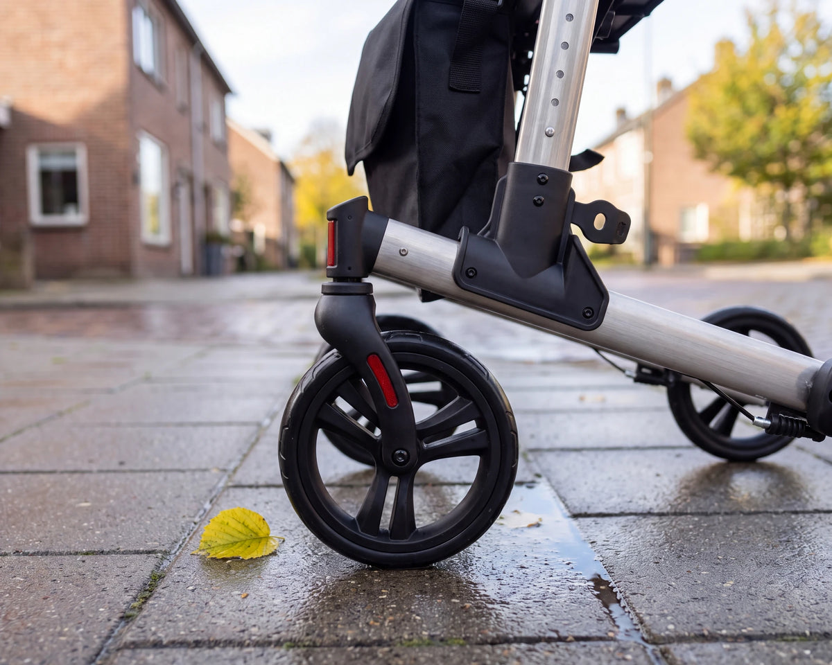 Close-up of the front wheel of the Parvum Riva in gray on wet paving stones with an autumn leaf.